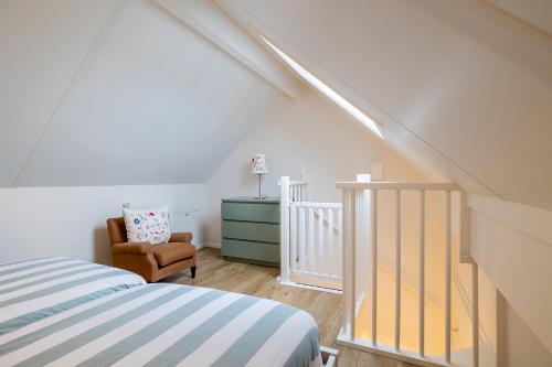 ein Schlafzimmer mit einem Bett und einem Stuhl im Dachgeschoss in der Unterkunft Villa Zuiderduin in Zoutelande