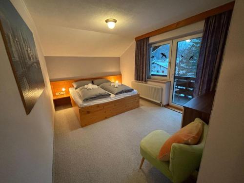 a bedroom with a bed and a window and a chair at Martins Apartmenthaus in Biberwier