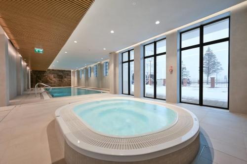 une grande salle de bains avec un bain à remous et une piscine dans l'établissement Marina Royale Darłowo - Apartamenty Ultra Mar nad morzem, à Darłówko