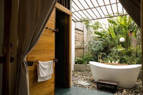 uma banheira na casa de banho com um jardim em Tổ Boutique Garden em La Gi