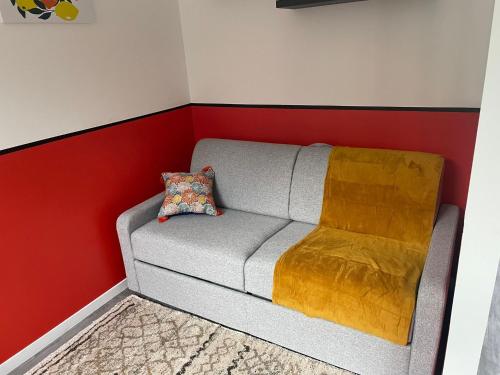 - un canapé dans une chambre dotée d'un mur rouge et blanc dans l'établissement Dahlia Studio -centre-ville, à Bolbec