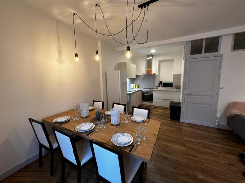 une table de salle à manger avec des chaises et une cuisine dans l'établissement Belle maison de ville au cœur du village de montagne, à Vic-sur-Cère