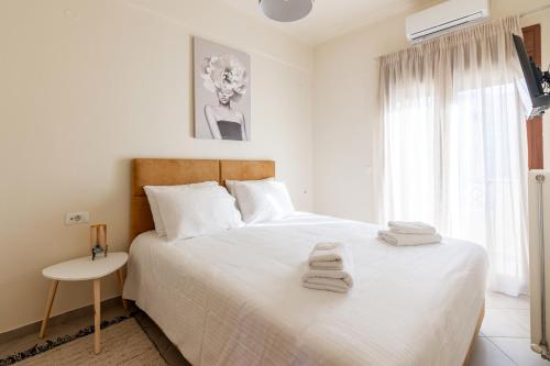 ein Schlafzimmer mit einem weißen Bett und Handtüchern darauf in der Unterkunft Zephyrus Cityscape Condo,By IdealStay Experience in Iraklio