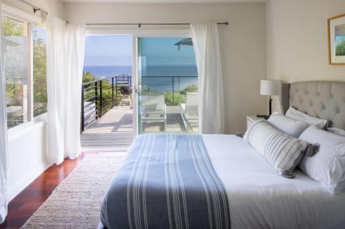 a bedroom with a bed and a balcony with the ocean at Bluff by AvantStay Gorgeous Malibu Getaway w Hot Tub Spectacular Ocean Views in Malibu