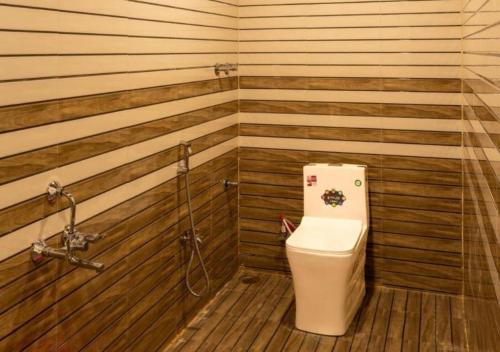 a bathroom with a toilet in a room with wooden walls at Areca Jungle Stays by StayApart in Potolai