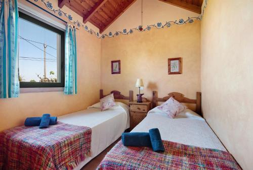 two beds in a room with a window at Casa Eco con vistas al Teide in La Orotava