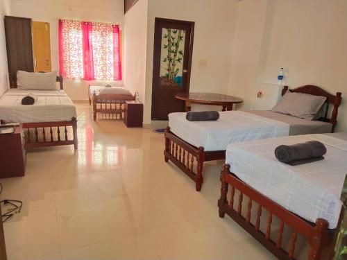 a room with three beds and a table in it at The Banyan Tree Samudra in Kovalam