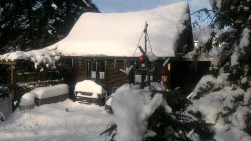 une maison recouverte de neige avec une voiture garée à l'extérieur dans l'établissement Blockhäusl am Jonsberg, à Jonsdorf