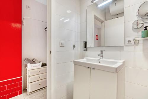 Baño blanco con lavabo y pared roja en Loft Cabanyal en Valencia