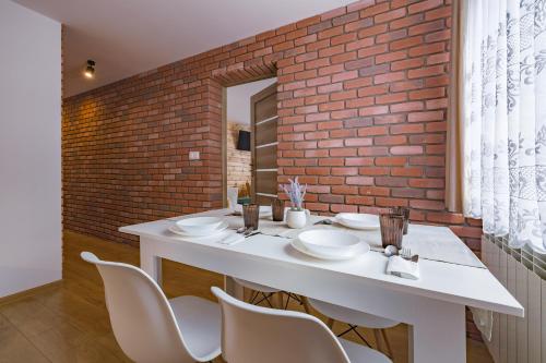 a dining room with a white table and a brick wall at Apartament u Wróbla in Leśnica