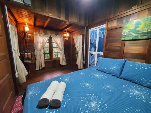 a bedroom with a blue bed with two rolled up towels at Alia Express Villa Temila in Pasir Puteh