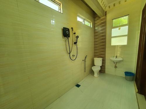 a bathroom with a toilet and a phone on the wall at Alia Express Villa Temila in Pasir Puteh