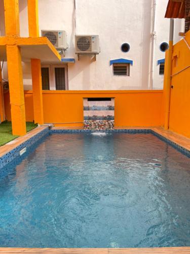 a swimming pool in a building with orange walls and water at Serenity Bay Home Stay in Pondicherry