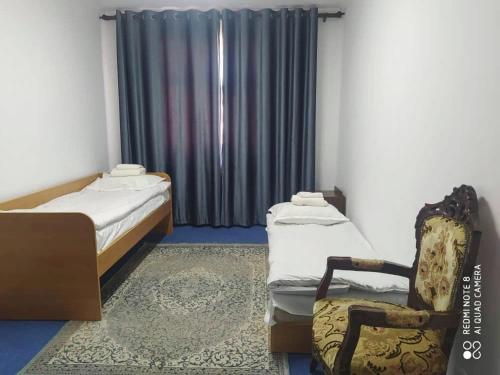 pokój z 2 łóżkami i krzesłem w obiekcie Гостевой дом Энесай w mieście Biszkek