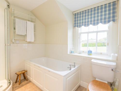 a white bathroom with a tub and a window at 4 Bed in Ancrum CA035 in Saint Boswells
