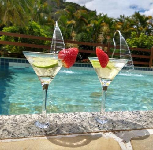 two martinis with a strawberry and lime on a ledge next to a pool at VILLA MIA DUO in Itaipava