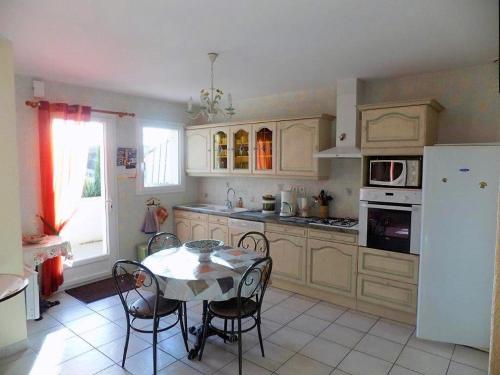 une cuisine avec une table et un réfrigérateur blanc dans l'établissement St Palais sur Mer - BELLES PRESTATIONS pour CETTE MAISON INDIVIDUELLE, à Saint-Palais-sur-Mer