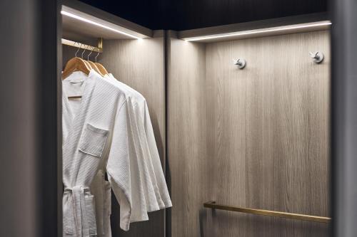 a closet with a white shirt hanging on a door at Novotel Singapore on Kitchener in Singapore