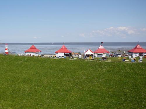 a group of buildings with red roofs next to the ocean at Hus Kiek in de See in Cuxhaven