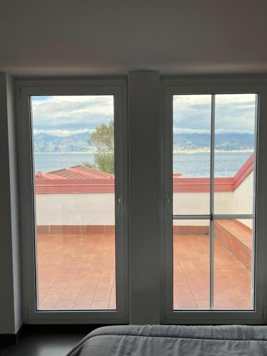 two windows in a bedroom with a view of the ocean at Thalassa Suite & Spa in Reggio Calabria