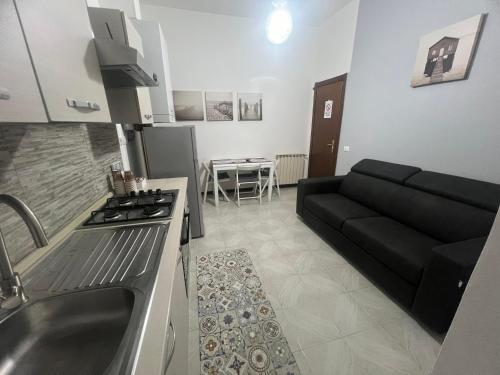 een keuken en een woonkamer met een zwarte bank bij Camere Andrea in La Spezia