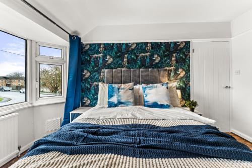 a bedroom with a large bed with a blue wall at Enchanting Abode in Cambridge - Pet Friendly! in Cherry Hinton