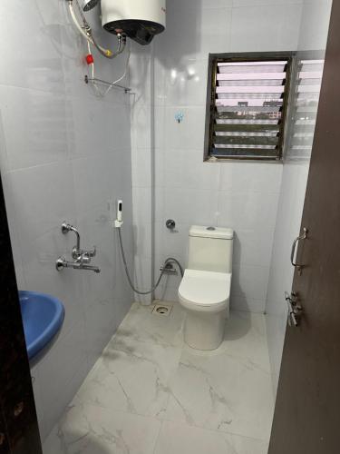 a white bathroom with a toilet and a sink at Jade Apartments- WiFi AC Smart Tv Kitchen in Pune