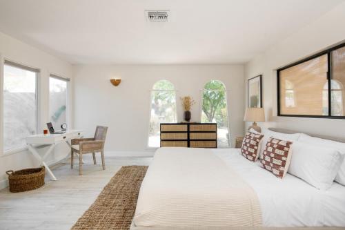 een witte slaapkamer met een groot bed en een bureau bij Archie by AvantStay Desert Retreat w Courtyard Edge of Joshua Tree in Yucca Valley