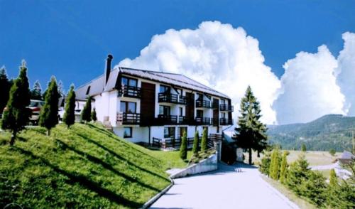 una casa en la cima de una colina con árboles y una carretera en Apartment Vlašićka Priča en Vlasic