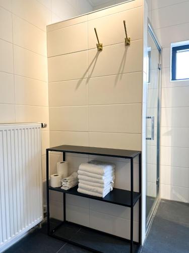 a bathroom with a black shelf with towels at Bed & Breakfast Waterpoort - incl licht ontbijt, airco en parking in Sneek
