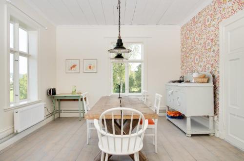 uma sala de jantar com uma mesa de madeira e cadeiras brancas em B&B Bjärtrå em Hjälta