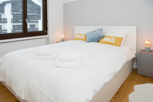 Cama blanca en habitación con ventana en Sundroina holiday flat for two people Lenzerheide centre, en Lenzerheide