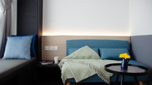 a bedroom with a blue bed and a table with a vase on it at VicHaus Serviced Apartment in Singapore