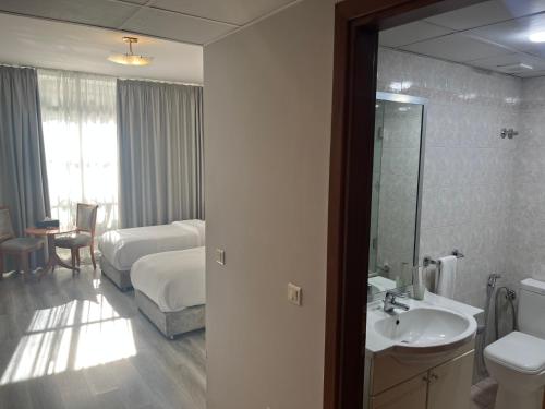 uma casa de banho com uma cama, um lavatório e um espelho. em El Sheikh Suites Hotel em Beirute