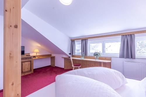 a bedroom with a bed and a desk with a computer at Hotel Sonnenheim in Sankt Anton am Arlberg
