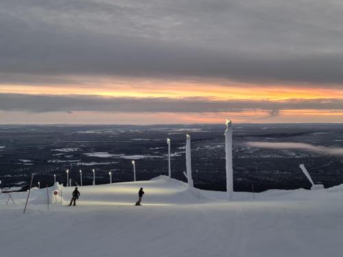 two people skiing down a snow covered slope at sunset at Polar Charm A in Ylläs