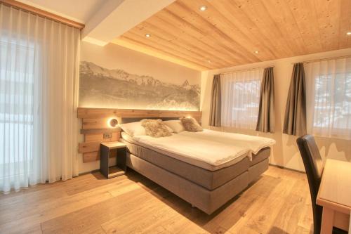 Matterhorngruss Apartments في زيرمات: غرفة نوم بسرير كبير في غرفة بها نوافذ