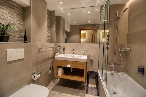 Matterhorngruss Apartments في زيرمات: حمام مع حوض ودش ومرحاض