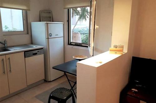 a kitchen with a refrigerator and a table and a window at Elia - seaside place in Agios Nikolaos