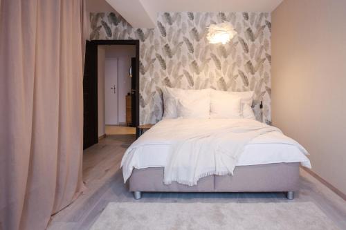 a bedroom with a white bed with a wall at Boutique Apartment 23 in Jáchymov