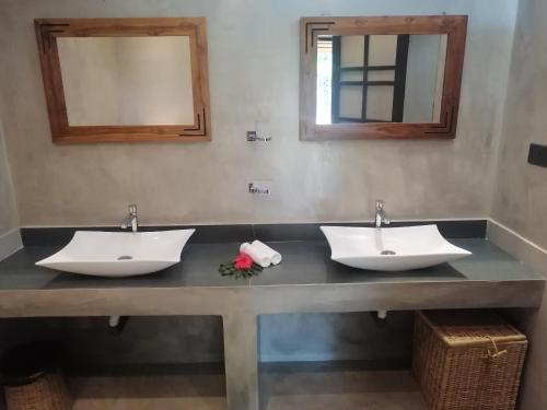 two sinks in a bathroom with two mirrors at Bappa's Place in Hiriketiya