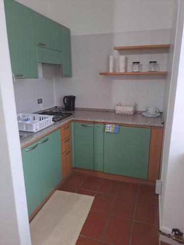een keuken met groene kasten en een tegelvloer bij Casa Vacanze Tavernella di Pam in Villa di Chiavenna