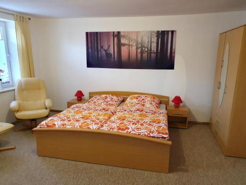 ein Schlafzimmer mit einem Bett und einem Stuhl in der Unterkunft Ferienwohnung Haus Flora in Hasselfelde