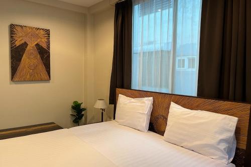 Baan Glang Soi في بانكوك: غرفة نوم بسرير وملاءات بيضاء ونافذة