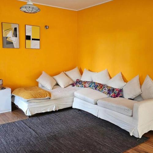 un sofá en una habitación con una pared de color naranja en Maravilloso espacio providencia, en Santiago