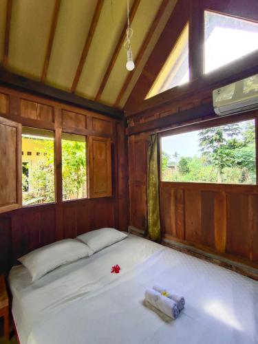 a bed in a room with two windows at Mettaloka Guesthouse in Magelang