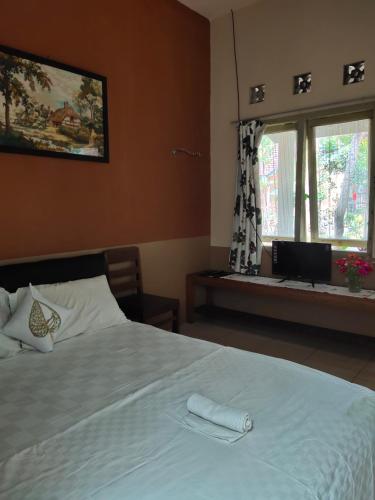 a bedroom with a large white bed with a window at Mettaloka Guesthouse in Magelang