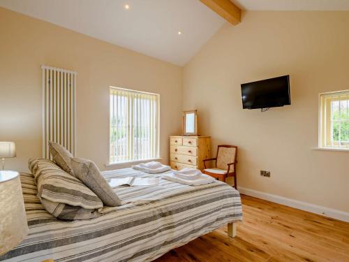 a bedroom with a bed and a tv on the wall at 3 Bed in Wroxham 83034 in Worstead