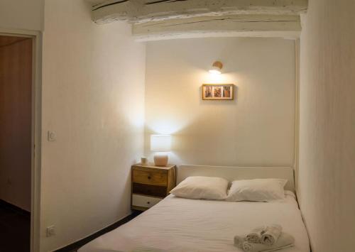 ein Schlafzimmer mit einem weißen Bett und einem Nachttisch in der Unterkunft Appartement avec cour privée + clim séjour + wifi in Avignon