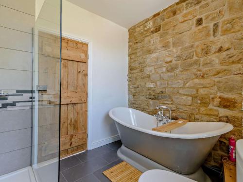 a bathroom with a tub and a stone wall at 3 Bed in Holmfirth 83151 in Holmfirth